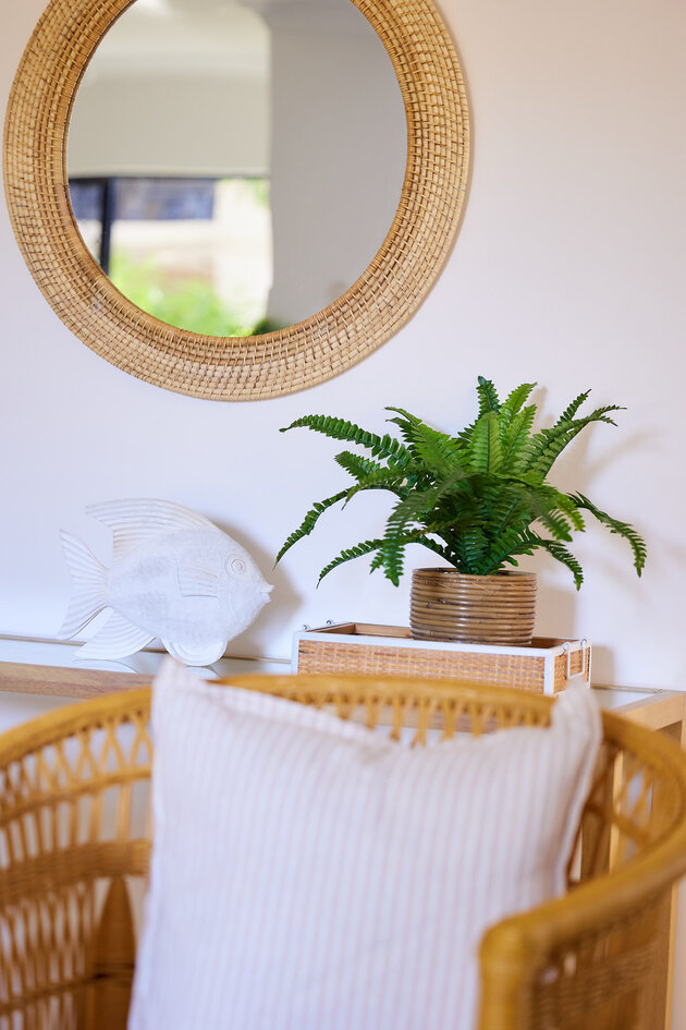 rental apartment with ratan style side table with fern and round mirror