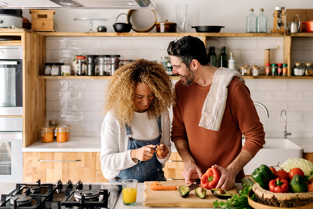 couple laughing in rental property while cooking and having a fabulous time